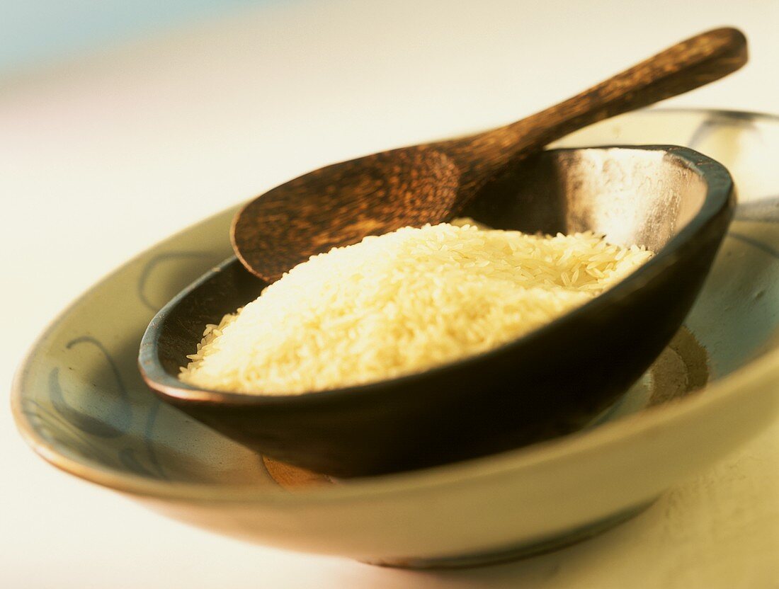 Reis in brauner Schale mit Holzlöffel