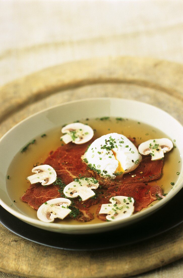 Carpaccio soup with poached egg and mushrooms