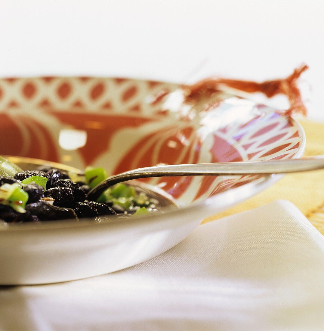 Schwarze Bohnensuppe mit grünem Paprika auf Teller mit Löffel