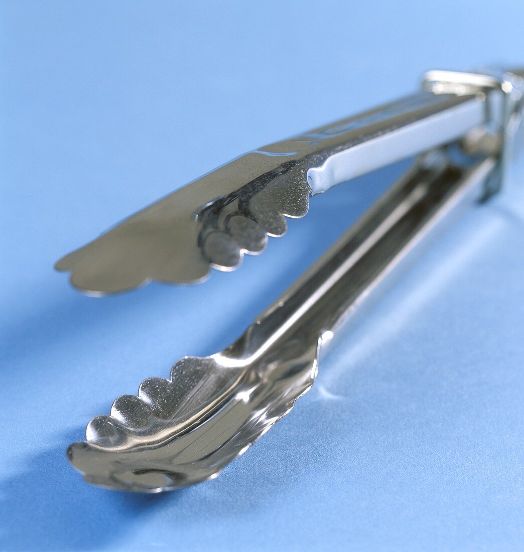 Barbecue tongs on blue background