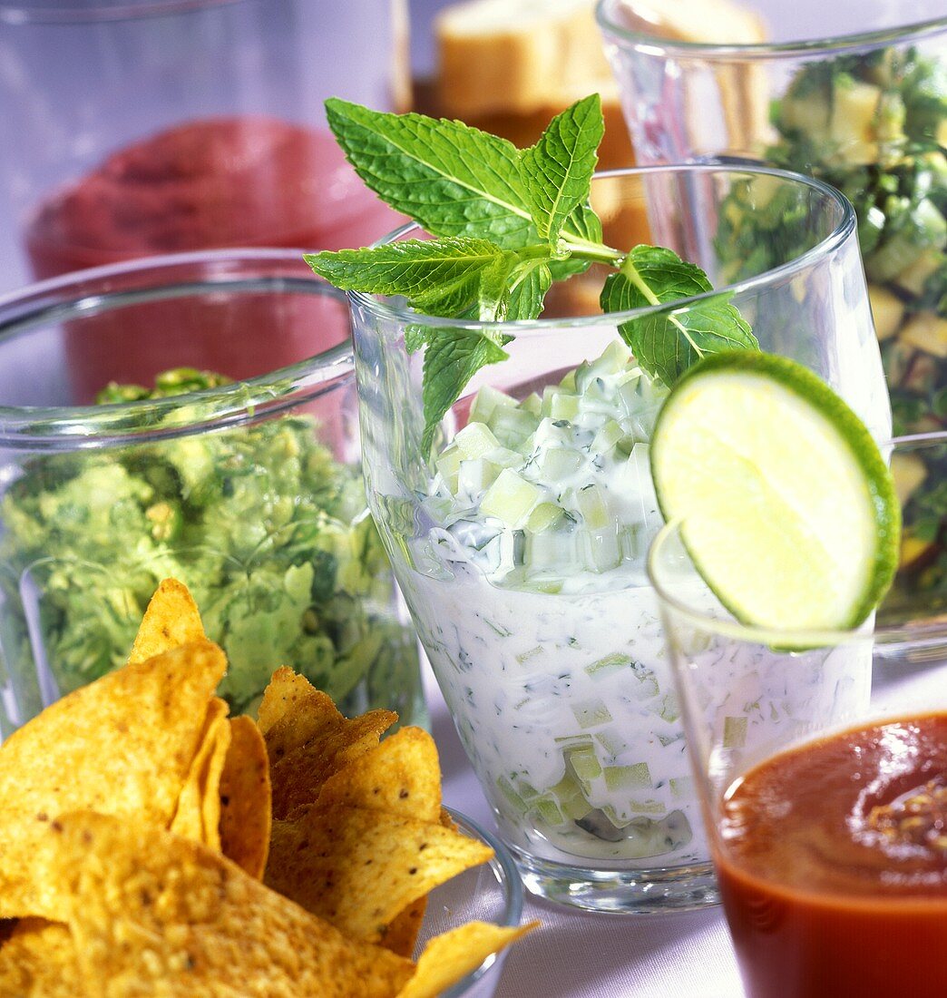 Various dips in glasses and tortilla chips