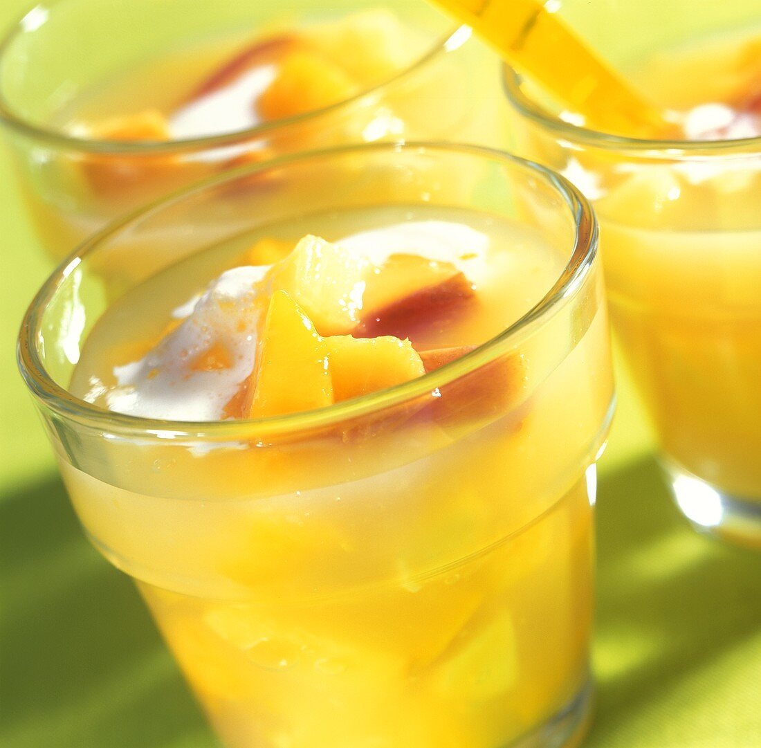 Yellow fruit compote with cream in glasses for summer party