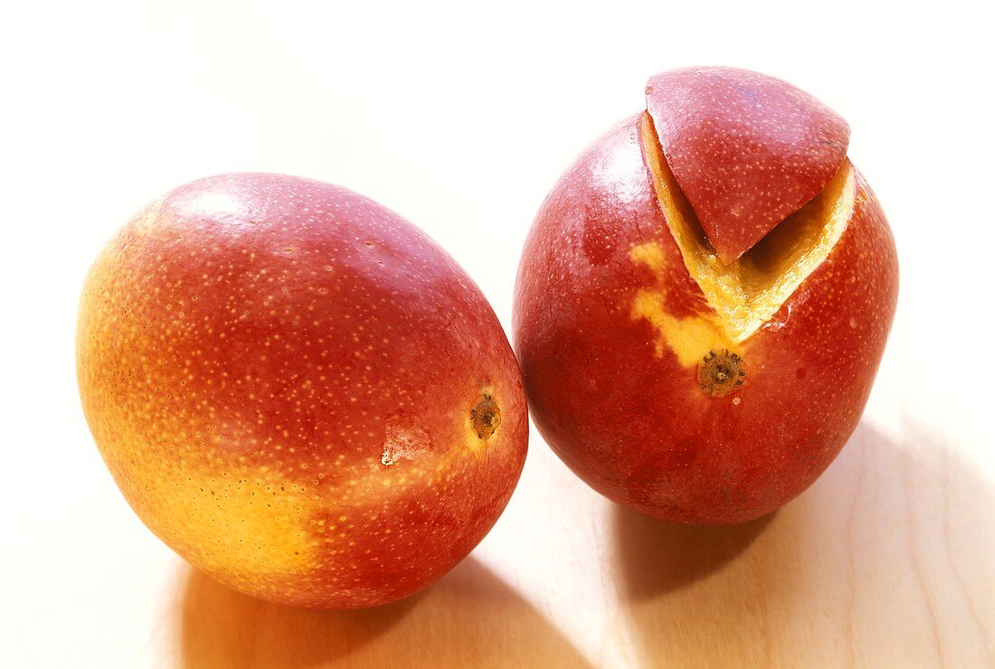 Mangos (Sensation variety), one with a piece cut off 