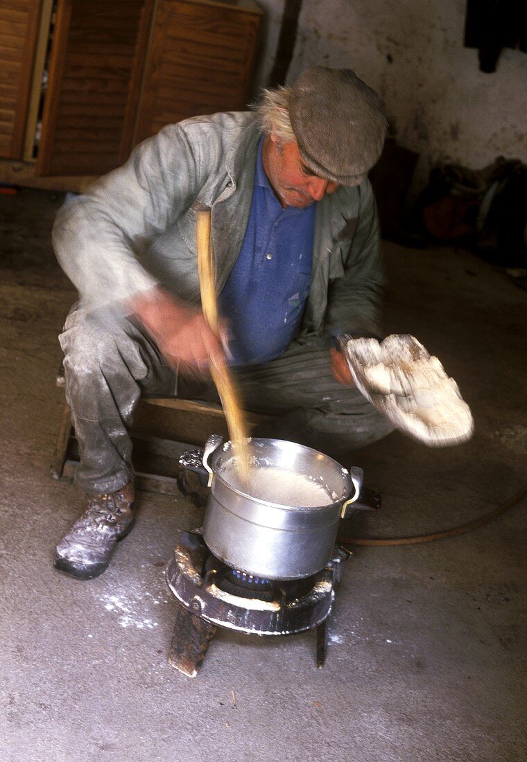 Corsican farmer cooking polenta on small gas stove