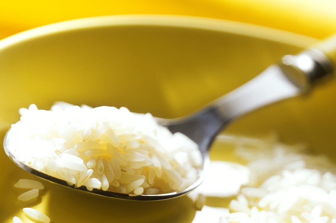 Reis auf Löffel über gelber Schale