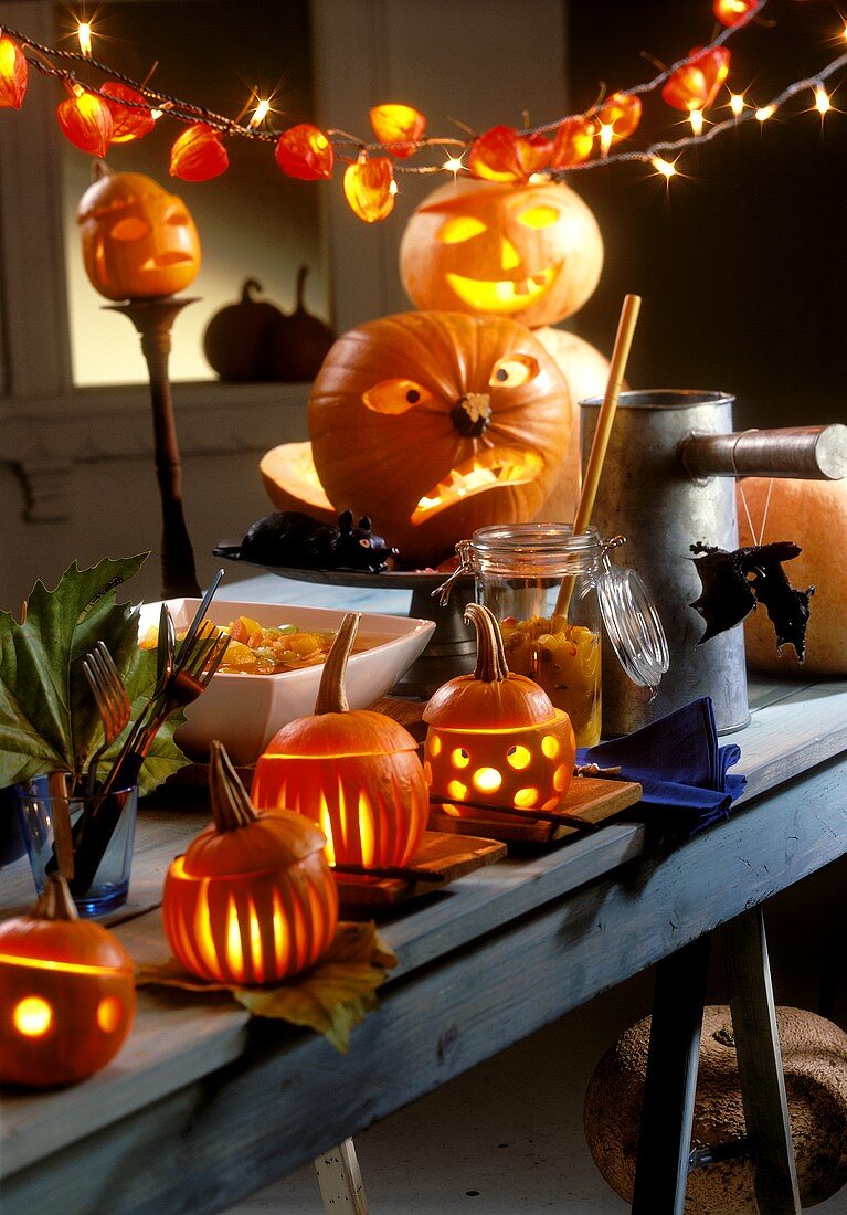 Gedeckter Tisch für Halloween mit beleuchteten Kürbissen