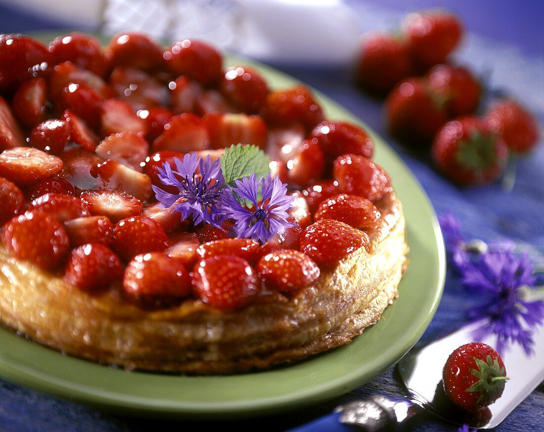 Strawberry tart in puff pastry with purple flowers