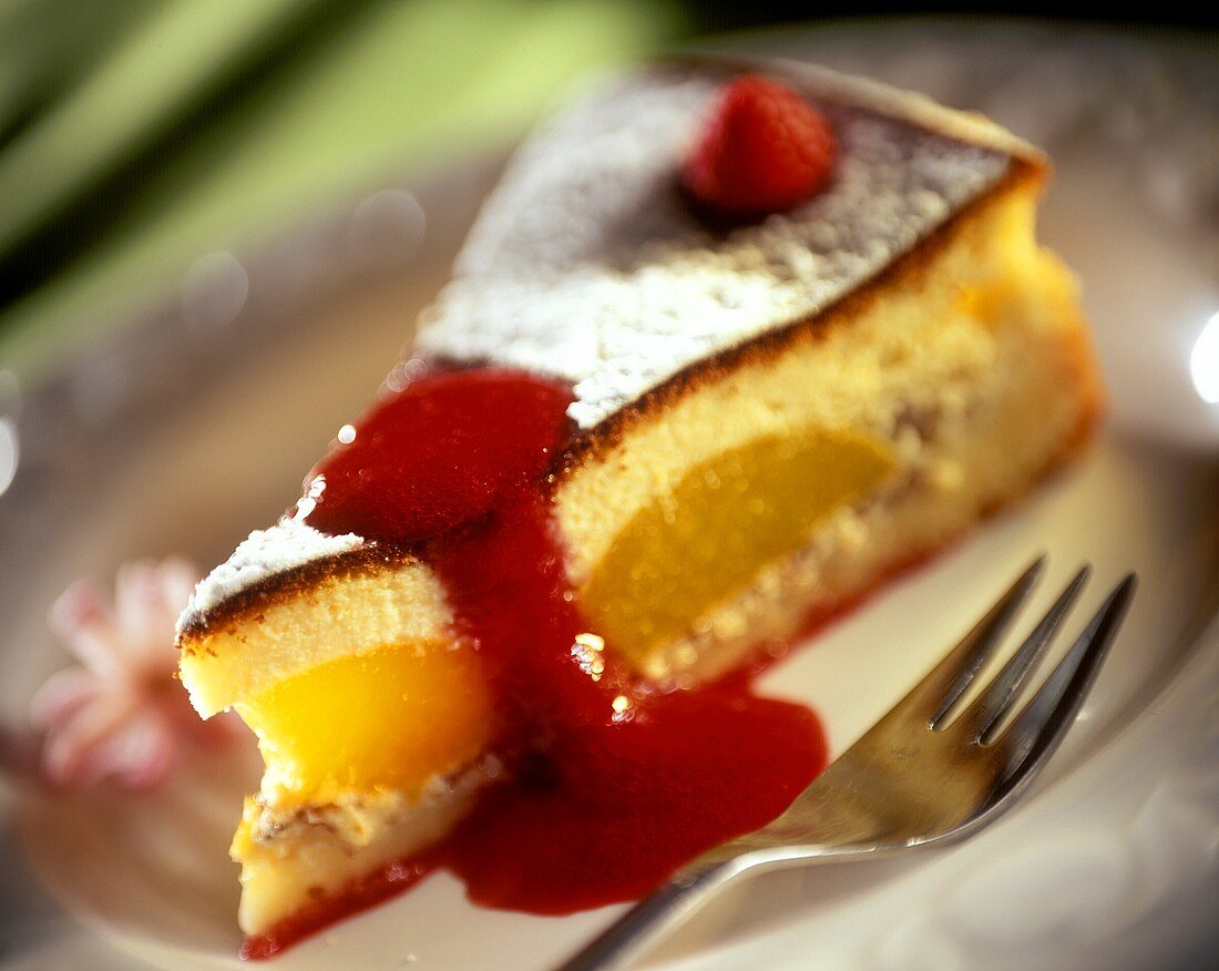 Piece of cheesecake with peaches and raspberry sauce