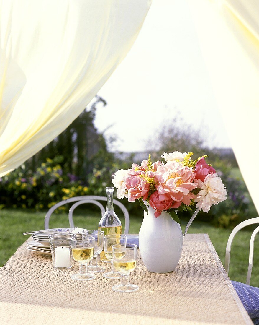 Table in open air with wine, candle and peonies