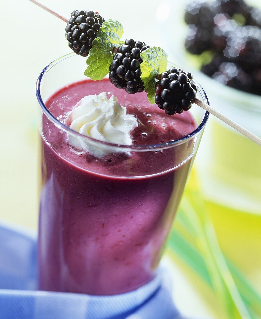 Berry shake with blob of cream and cocktail blackberry