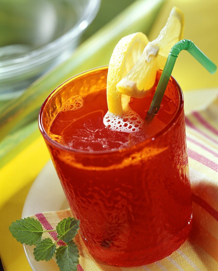 Fruit juice punch in red glass with lemon wedges
