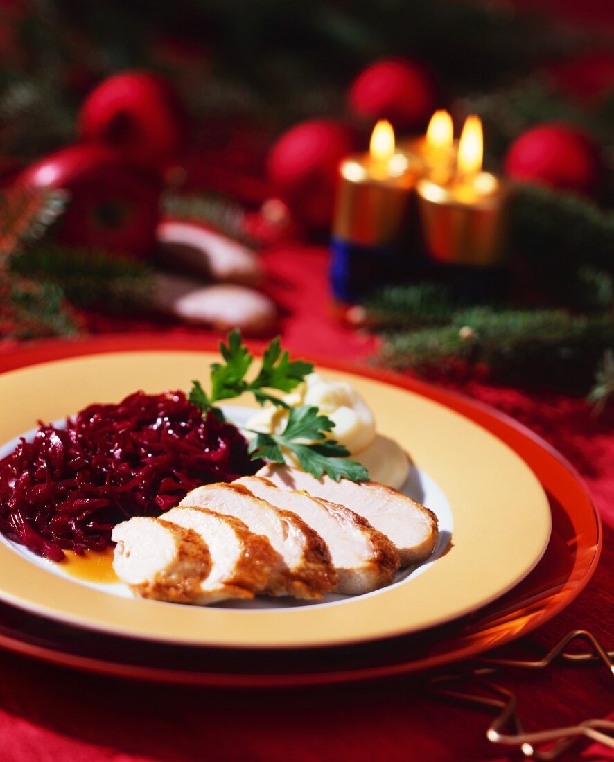 Putenbrust mit Rotkohl und Püree; Tannenzweige, Kerzen, Äpfel