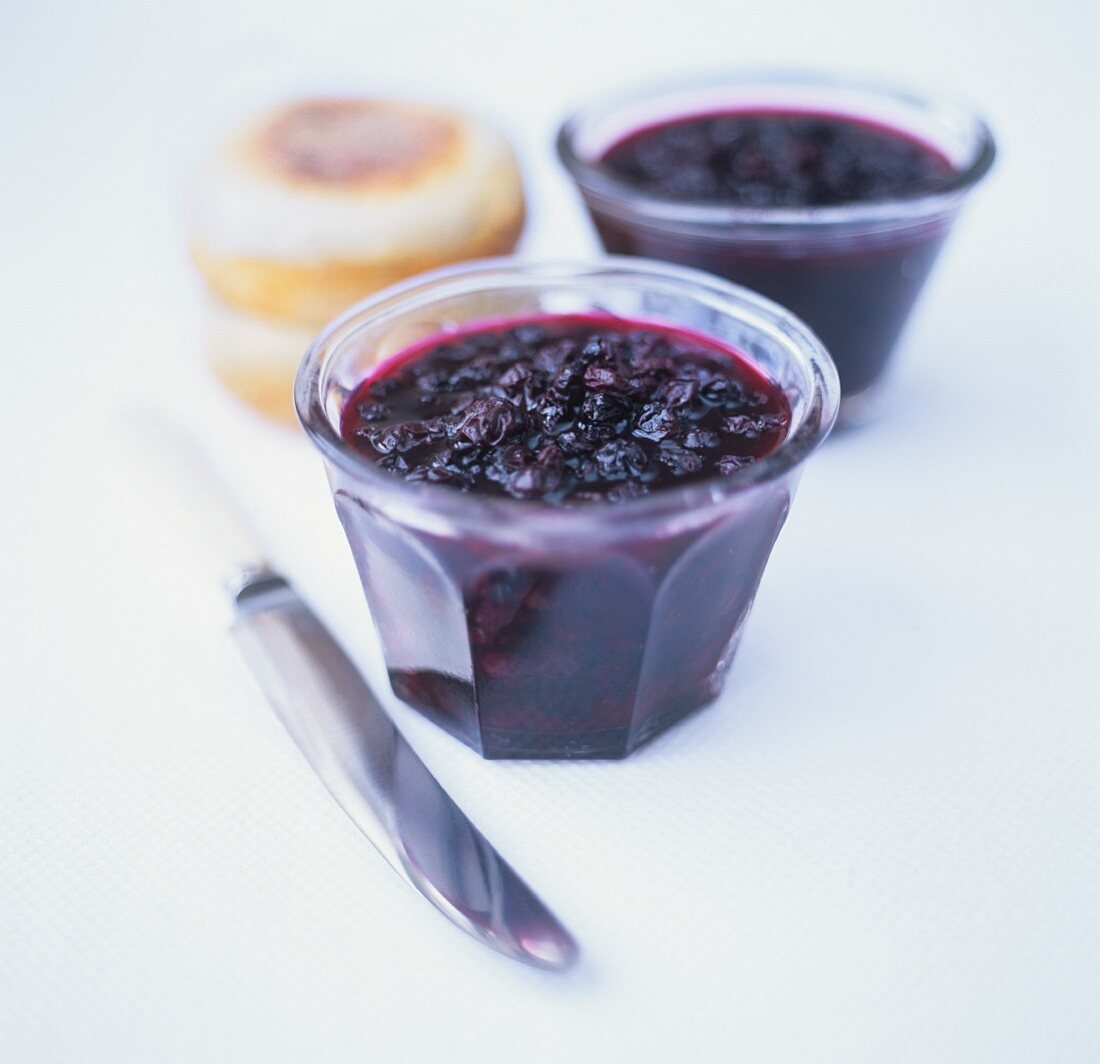 Blueberry jam in two jars; rolls