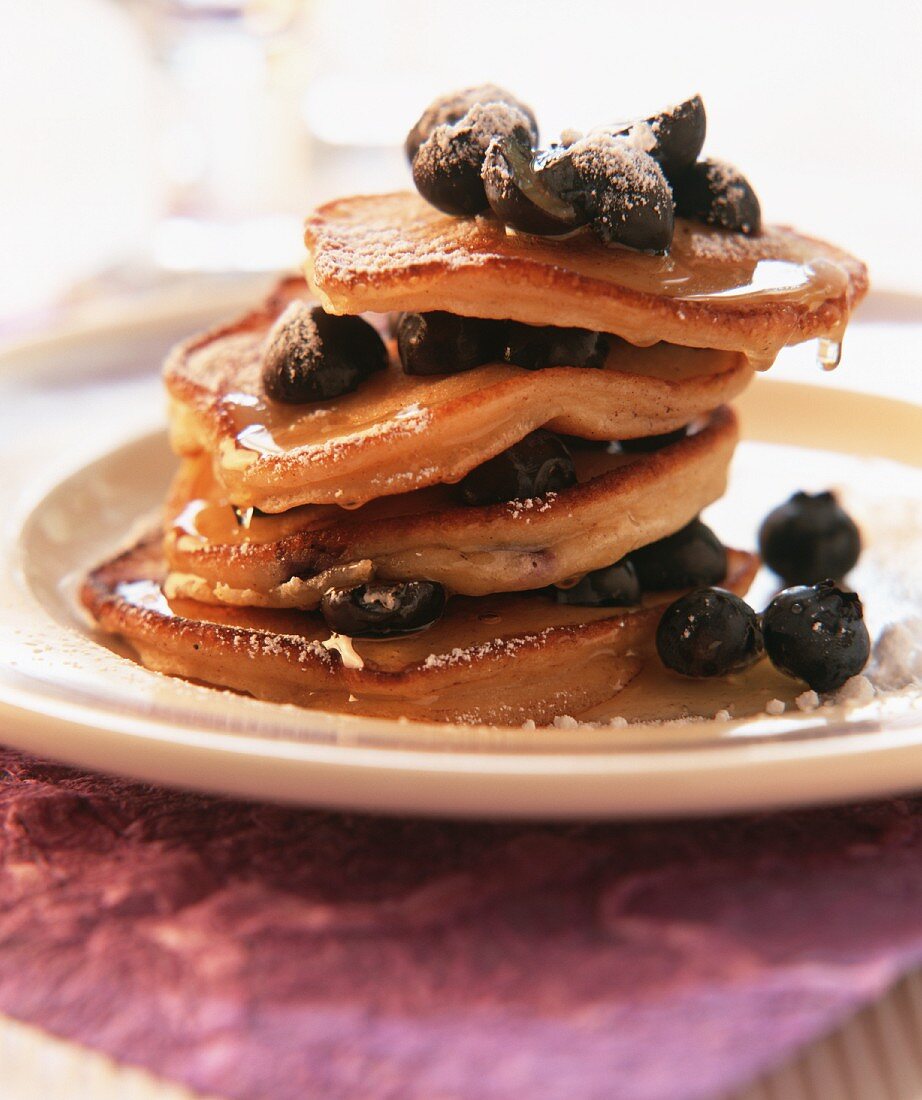 Pancakes with berries, icing sugar and maple syrup