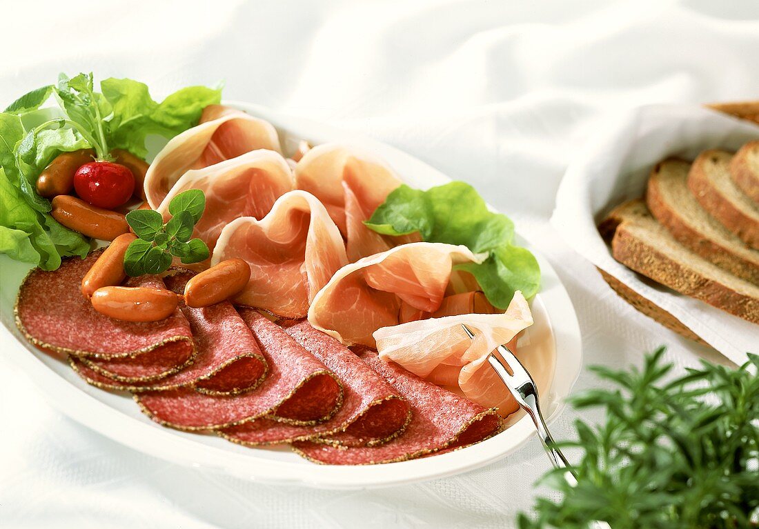 Sausage and ham platter with radishes; bread