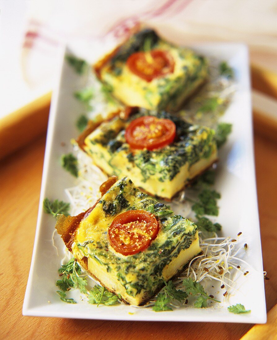 Spinach frittata with cherry tomatoes, cut into pieces
