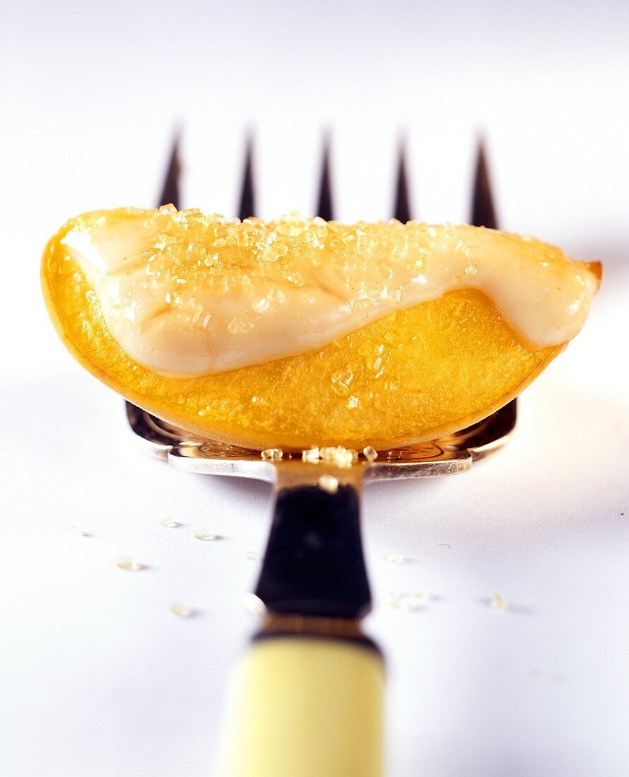 Peach wedge with lemon icing on fork