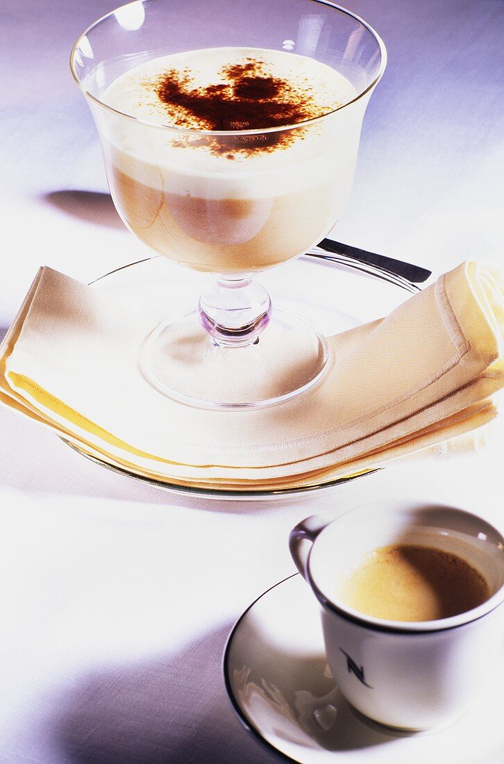 Coffee and vanilla cream in glass beside coffee cup
