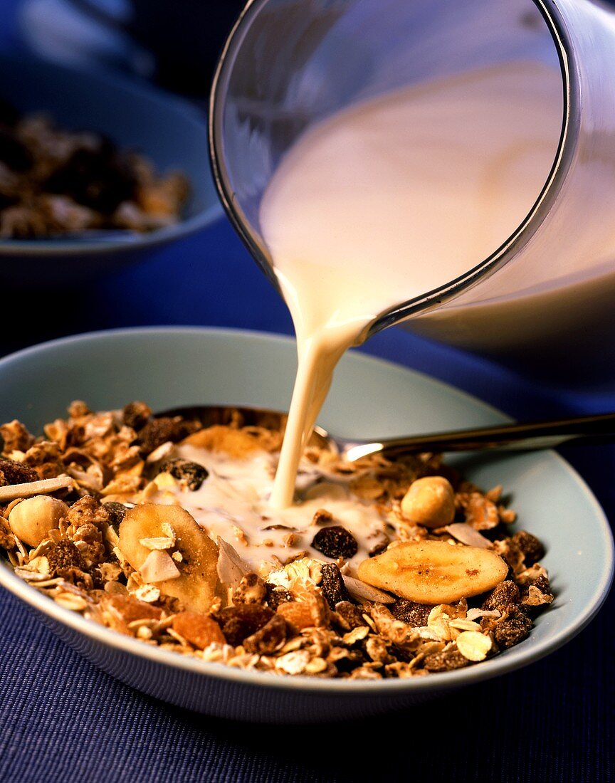 Pouring milk on to muesli with bananas