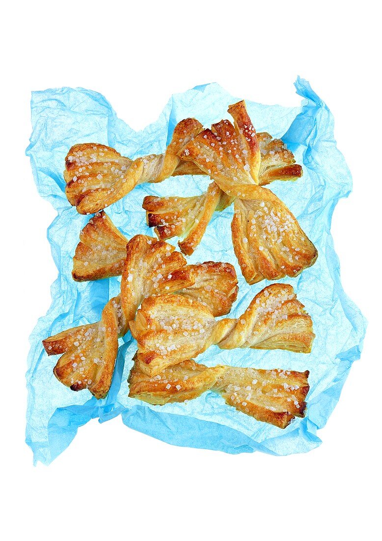 Puff pastry bows with sugar on blue paper