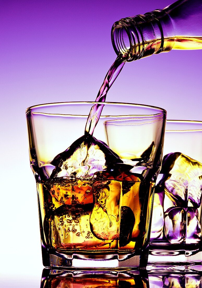 Whiskey in Glas mit Eiswürfeln einschenken