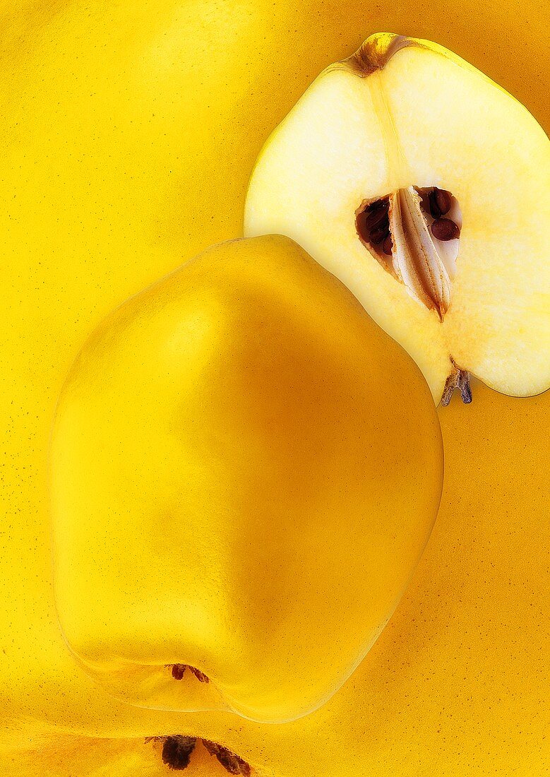 Whole and half quince against background of quinces