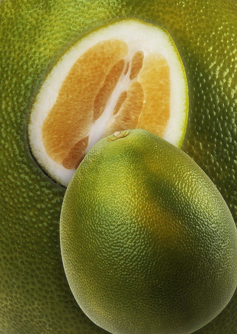 Ganze und halbe Pomelo auf Pomelo-Hintergrund