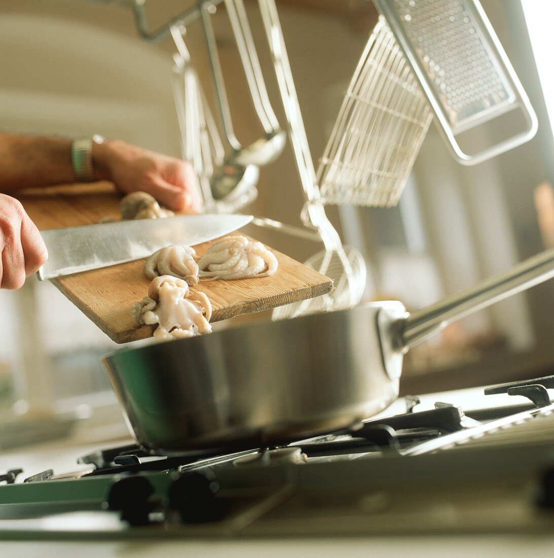 Transferring squid from chopping board into pan