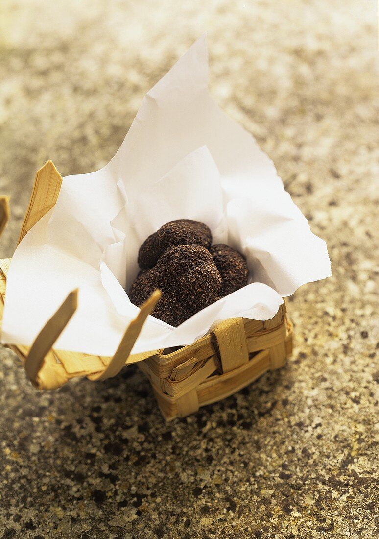 Black truffles in chip basket on stone background