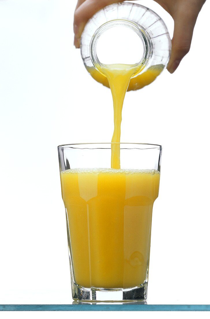 Pouring orange juice from a bottle into a glass