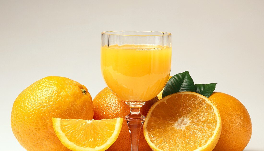 Glass of orange juice and fresh oranges