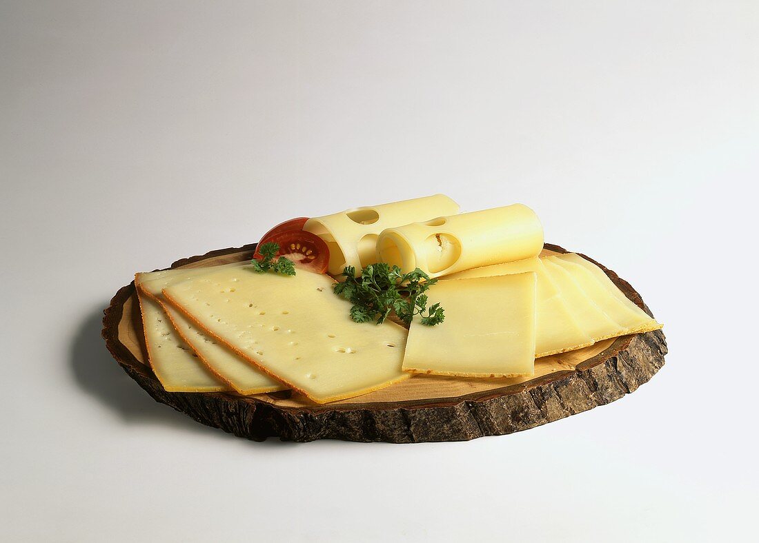 Various cheese slices on rustic wooden plate