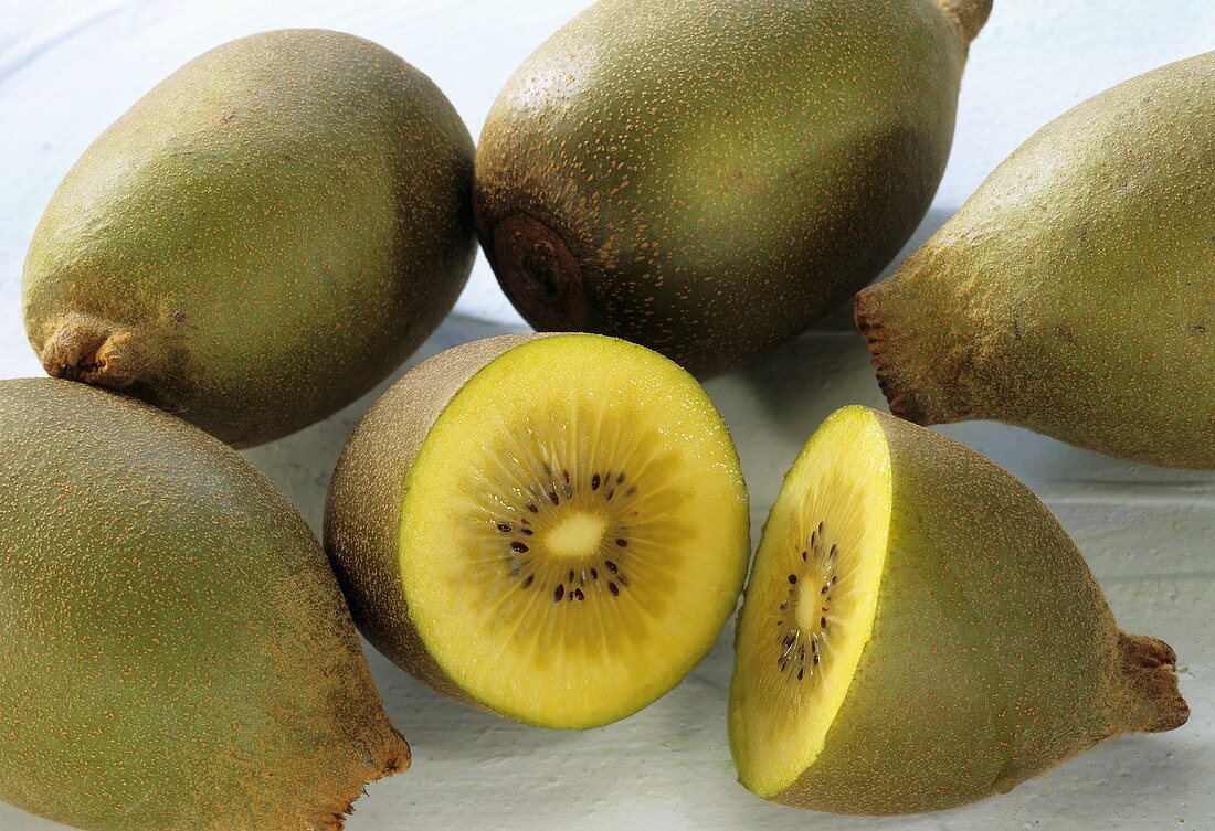 Yellow kiwi fruits, one halved