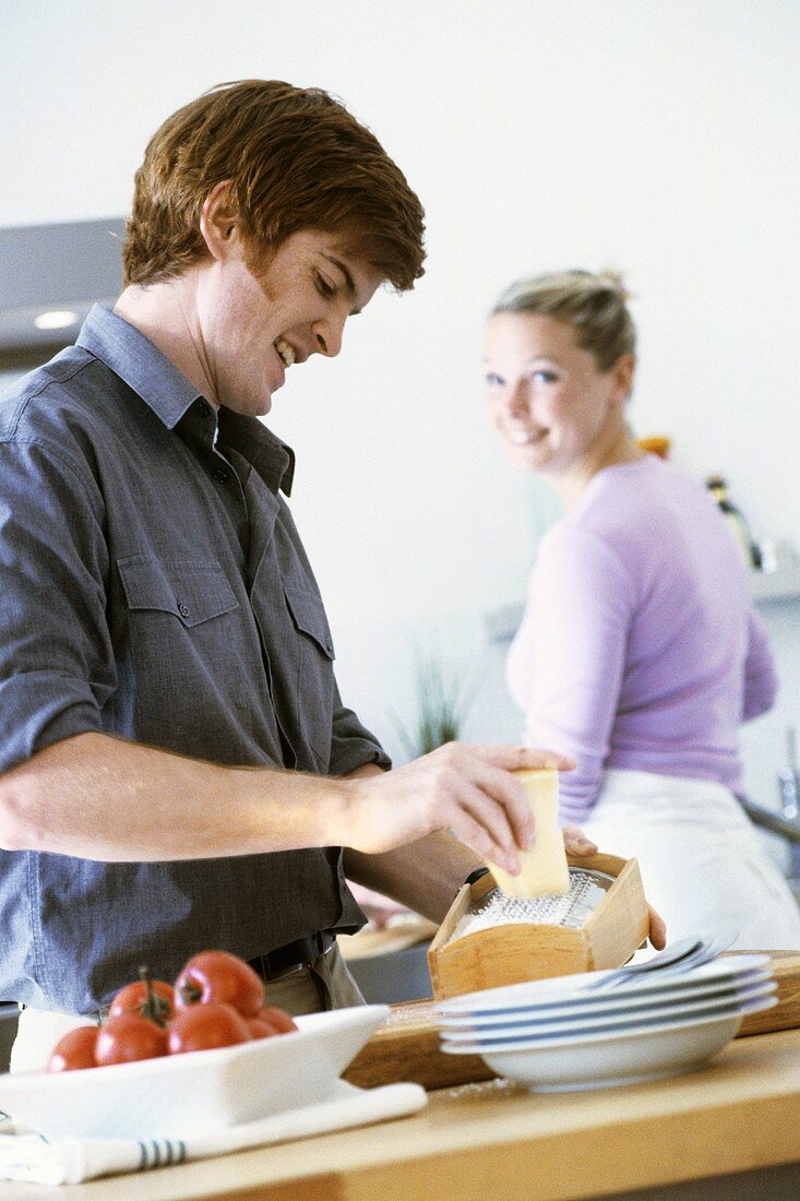 Junges Paar in der Küche (Mann reibt Käse)
