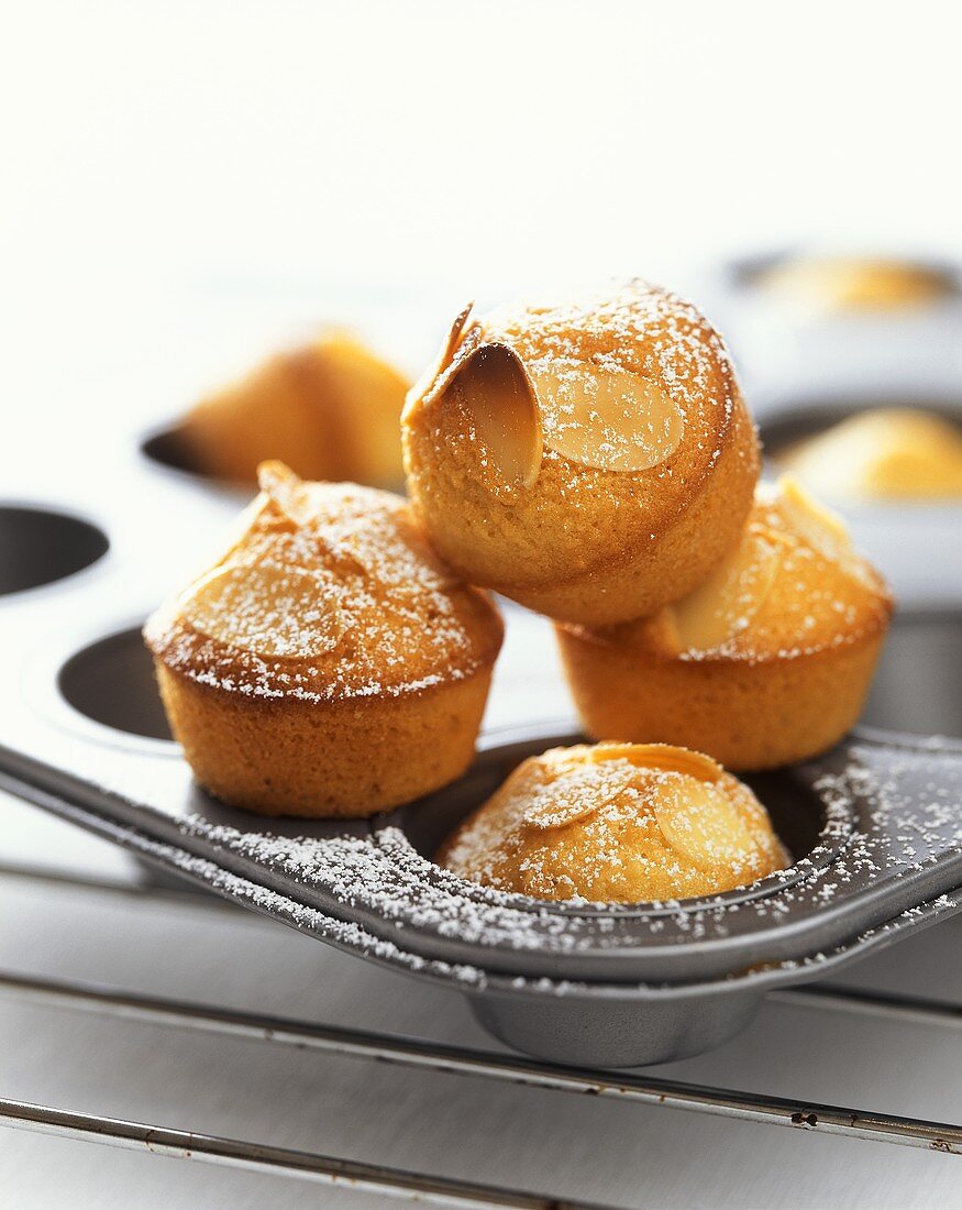 Almond muffins with icing sugar in muffin tin