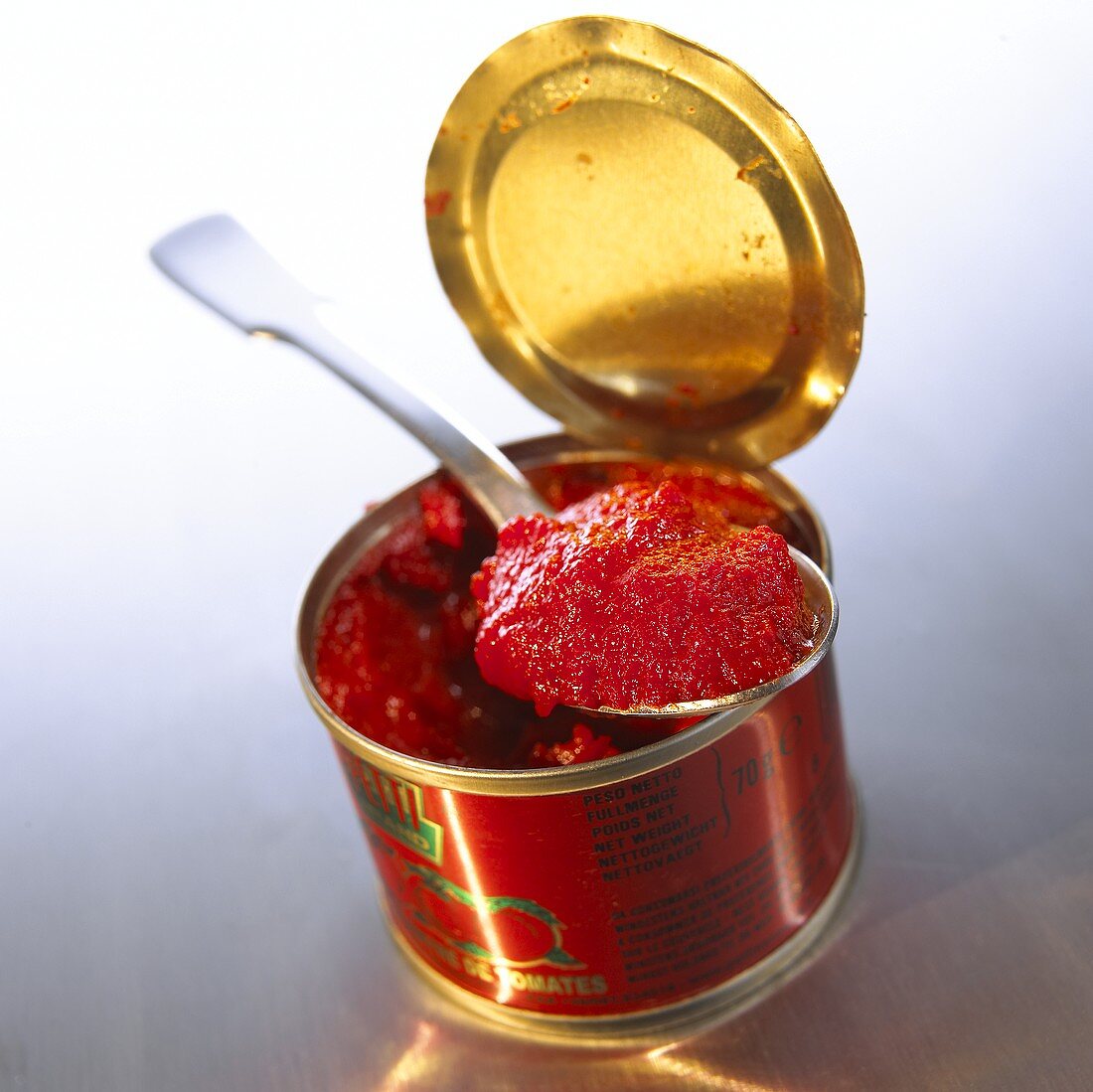 Tomato puree in tin and on spoon