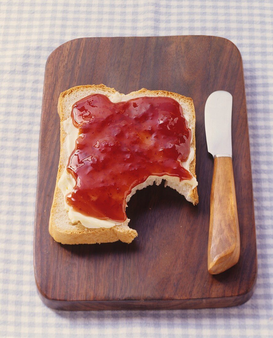 Bread with butter & strawberry jam on chopping board