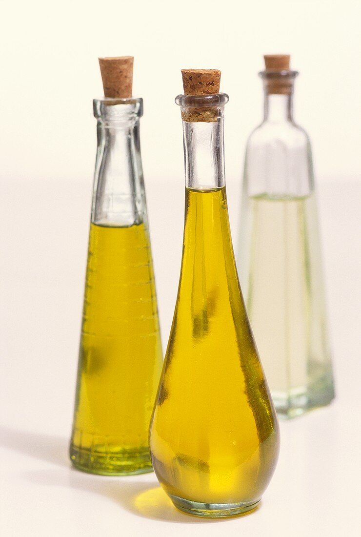 Zwei Flaschen Olivenöl und Flasche Weissweinessig