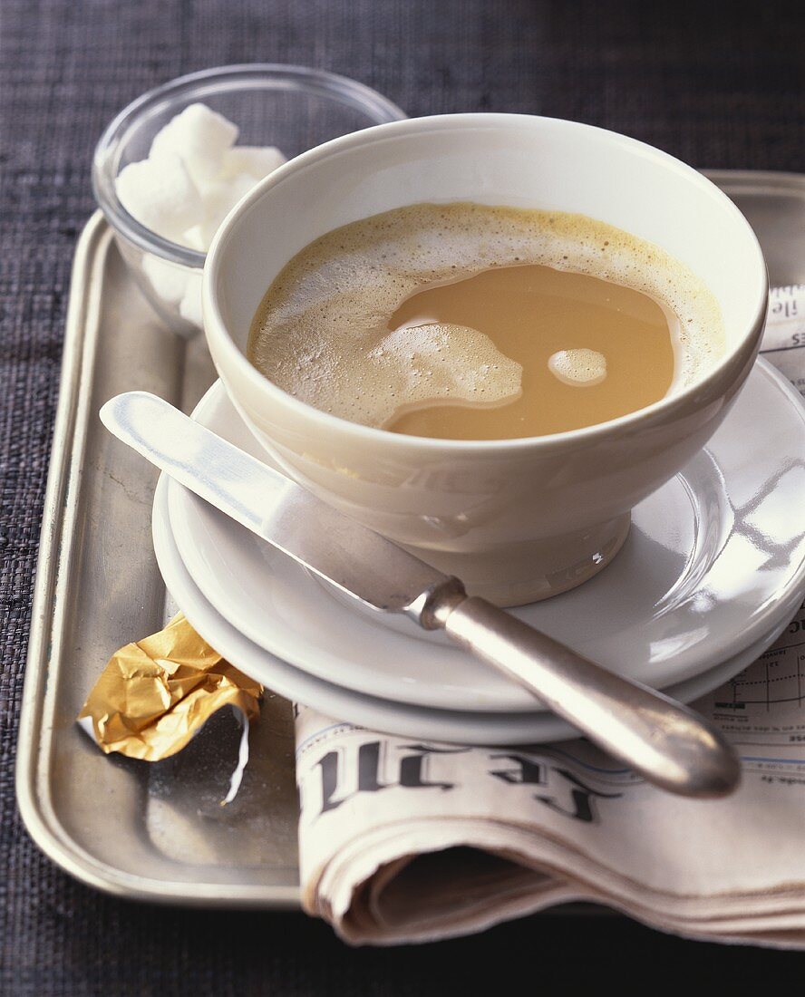 Tasse Milchkaffee auf französischer Zeitung