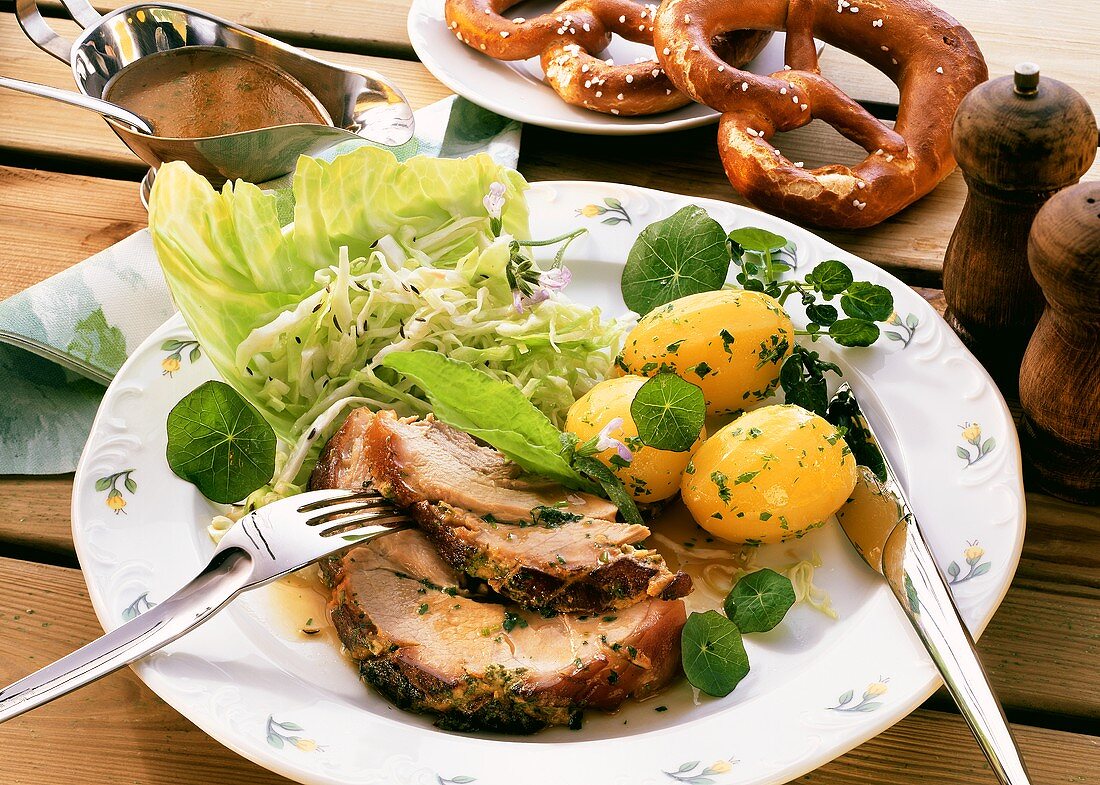 Roast pork with cabbage salad and boiled potatoes; pretzels