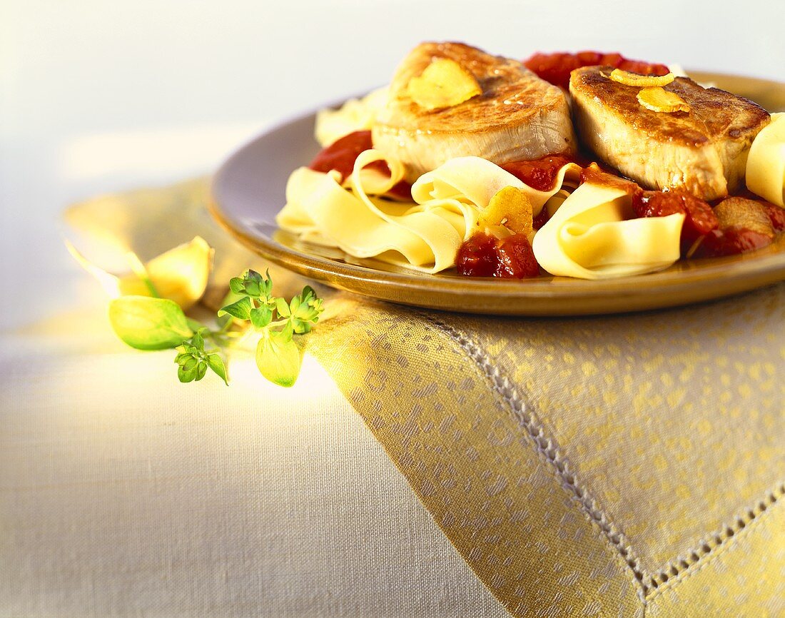 Pork chops in tomato and garlic sauce on ribbon pasta