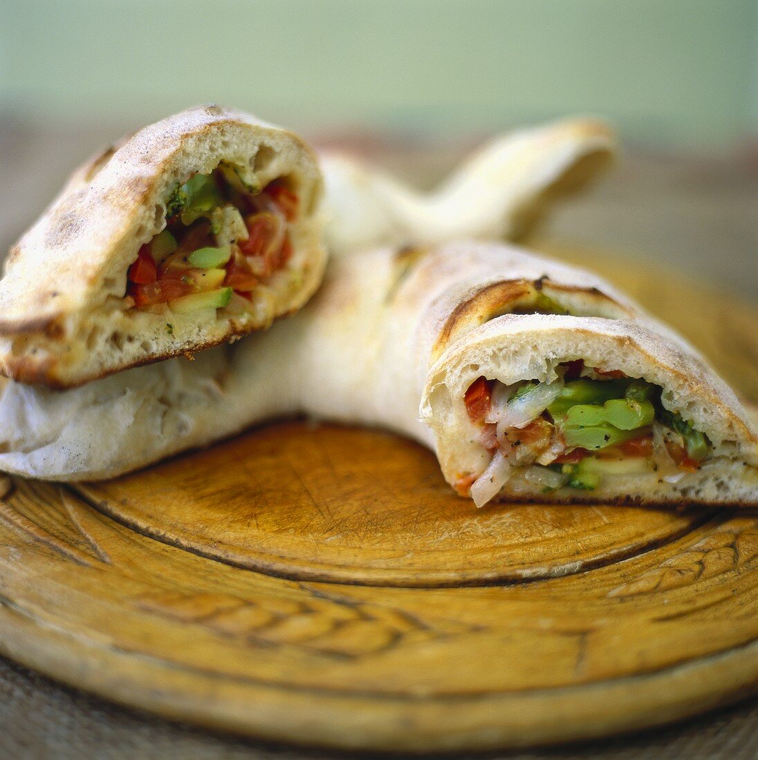 Tortello (round filled pizza) on wooden plate, a piece cut