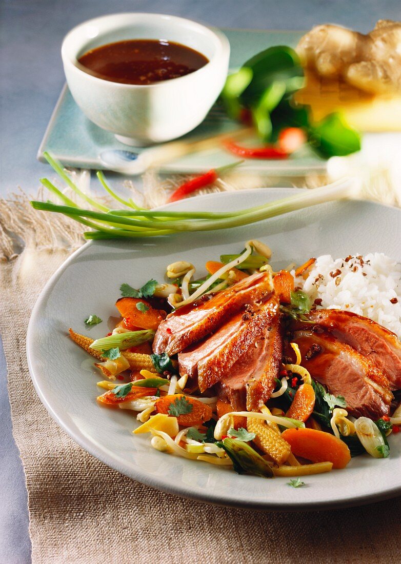 Sweet and sour duck breast with vegetables and rice; soy sauce