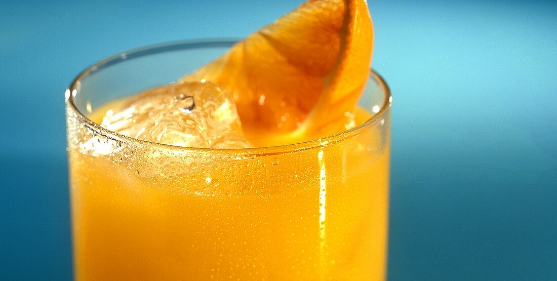 Glass of orange juice with ice cubes and orange wedge