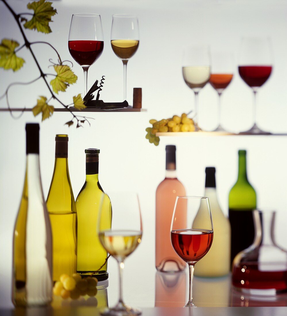 Various wine bottles and glasses; grapes; vine leaves