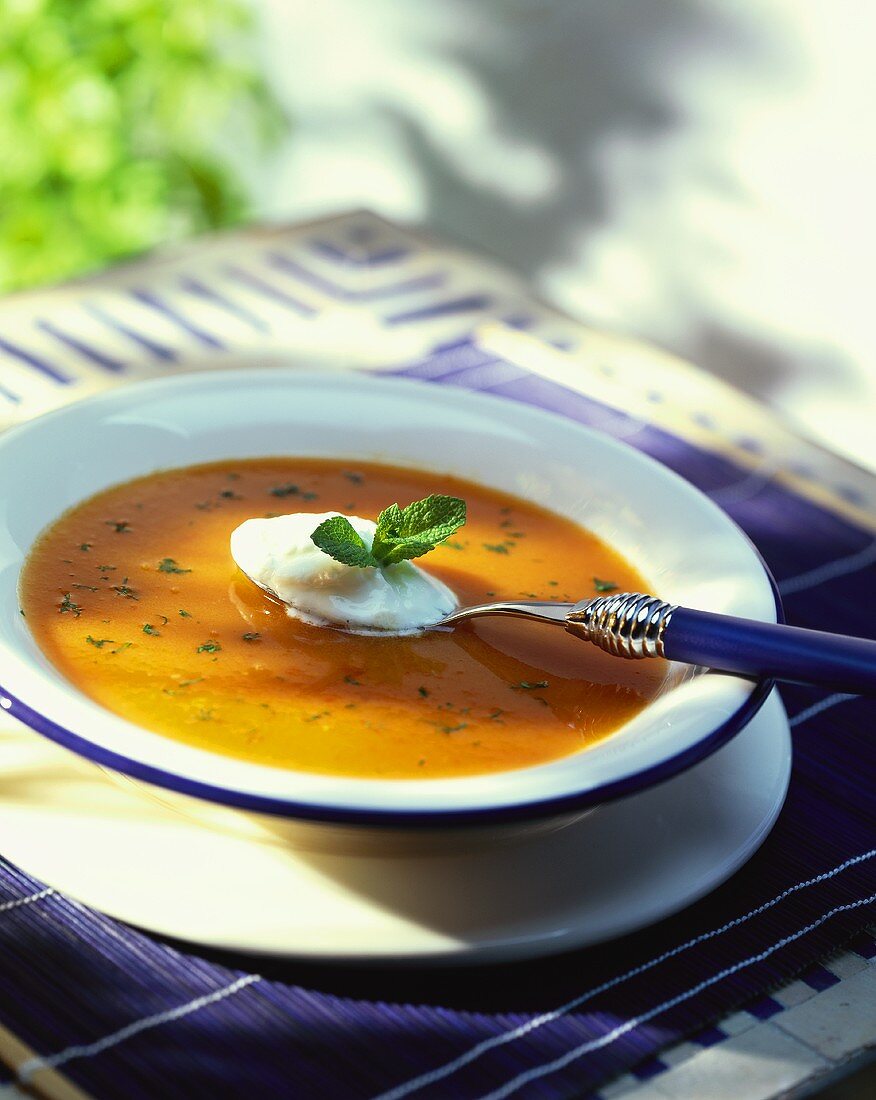 Carrot soup with spoonful of sour cream and mint