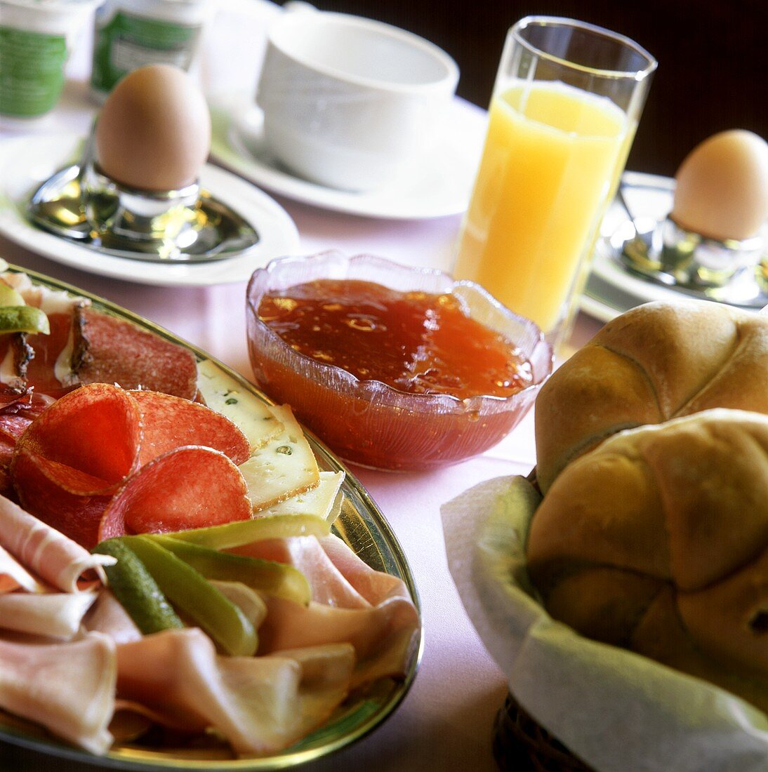 Frühstück mit Wurst, Brötchen, Marmelade, Ei und Orangensaft