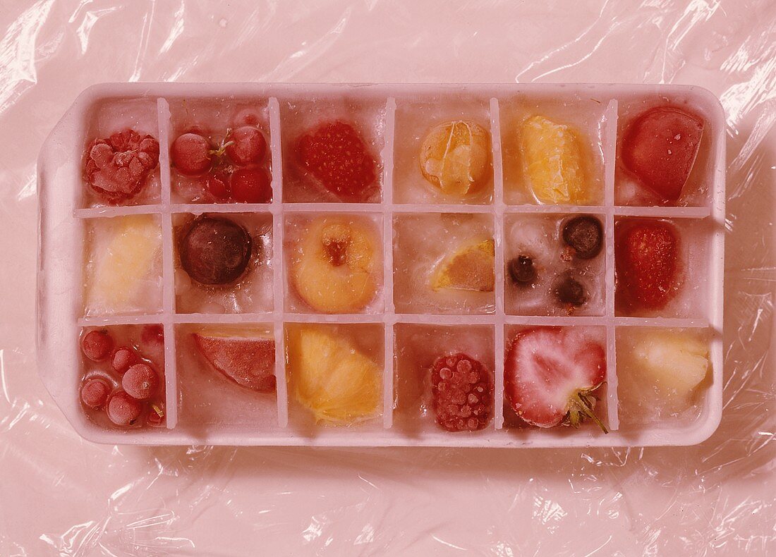 Eiswürfel mit gefrorenem Obst im Eiswürfelbehälter