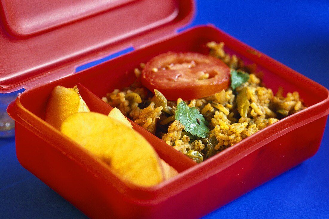 Lunchbox mit indischem Reisgericht (Biryani) und Äpfeln