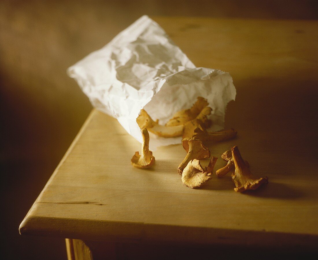 Chanterelles with paper bag on wooden table